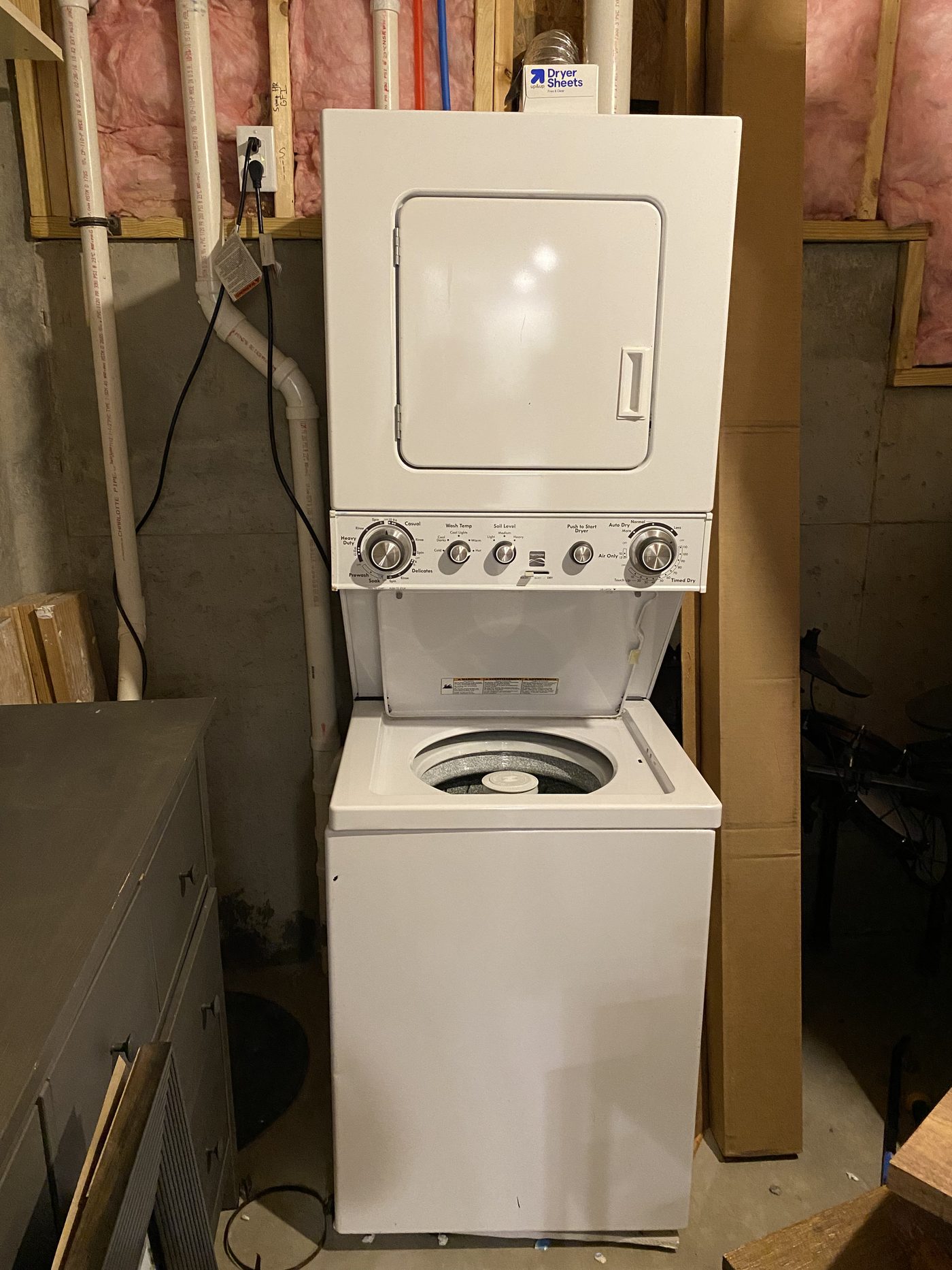 Stacked washer and dryer unit installed at a basement laundry hookup